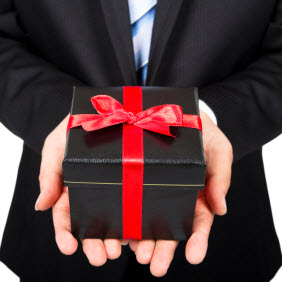 man in suit holding a boxed gift with a red ribbon