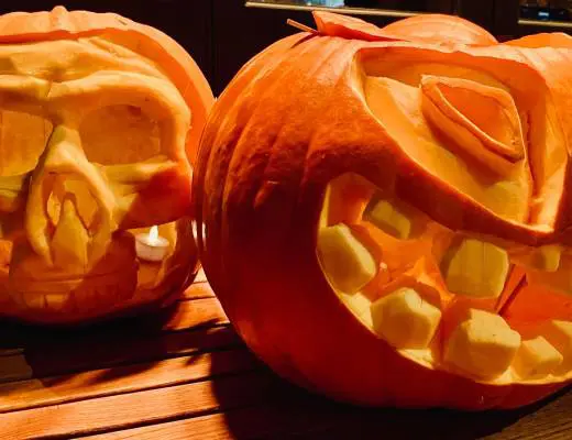 two carved pumpkins sitting on top of a wooden table