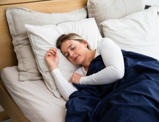a woman sleeping on a mattress with a blue blanket