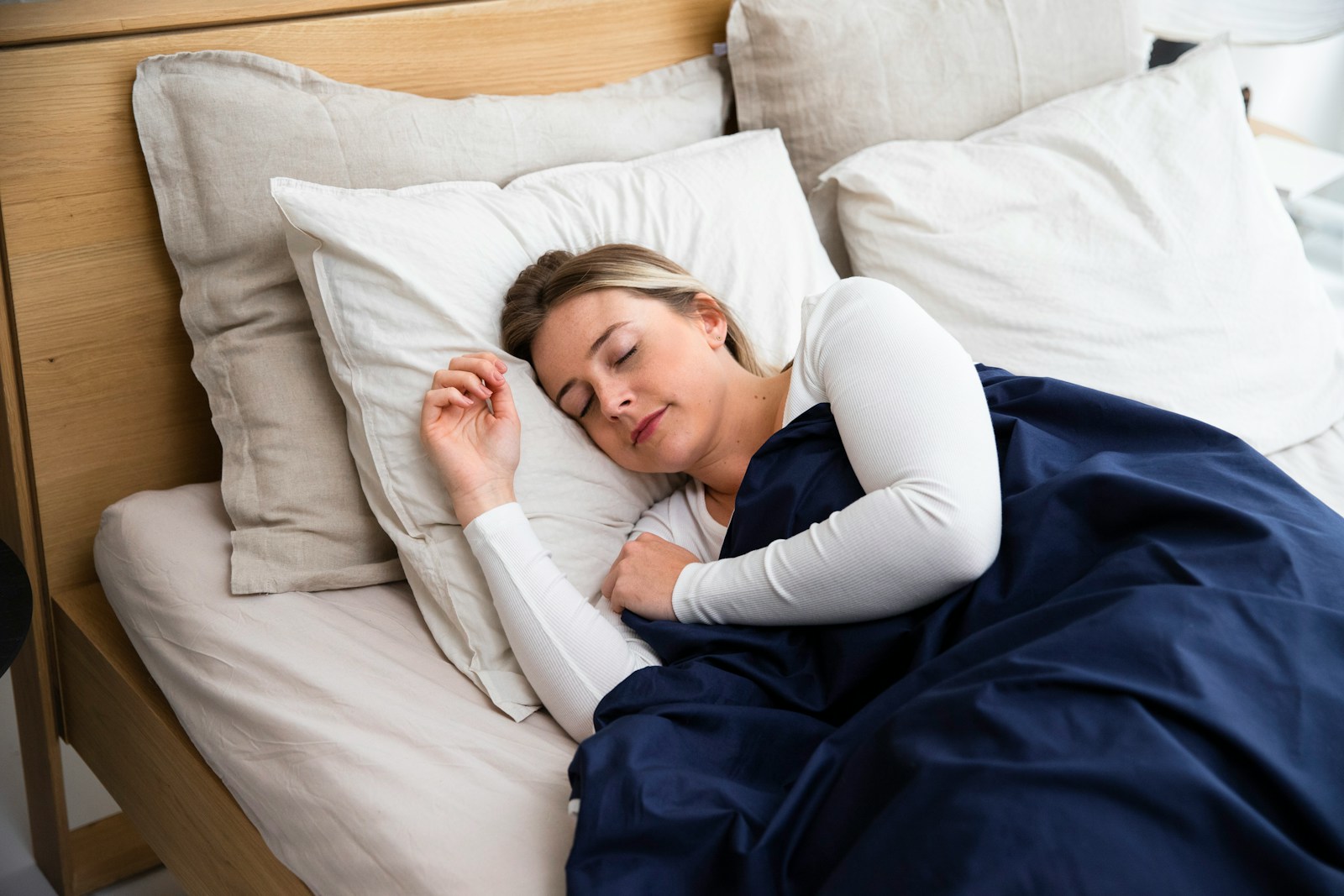 a woman sleeping on a mattress with a blue blanket