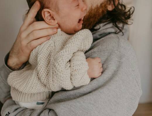 a man holding a crying baby in his arms showing signs of overstimulation
