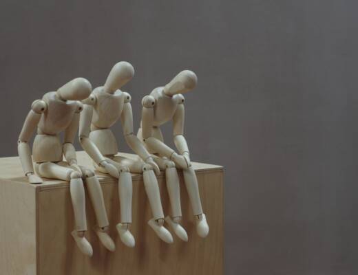 a group of wooden mannequins sitting on top of a wooden block; Decision Fatigue