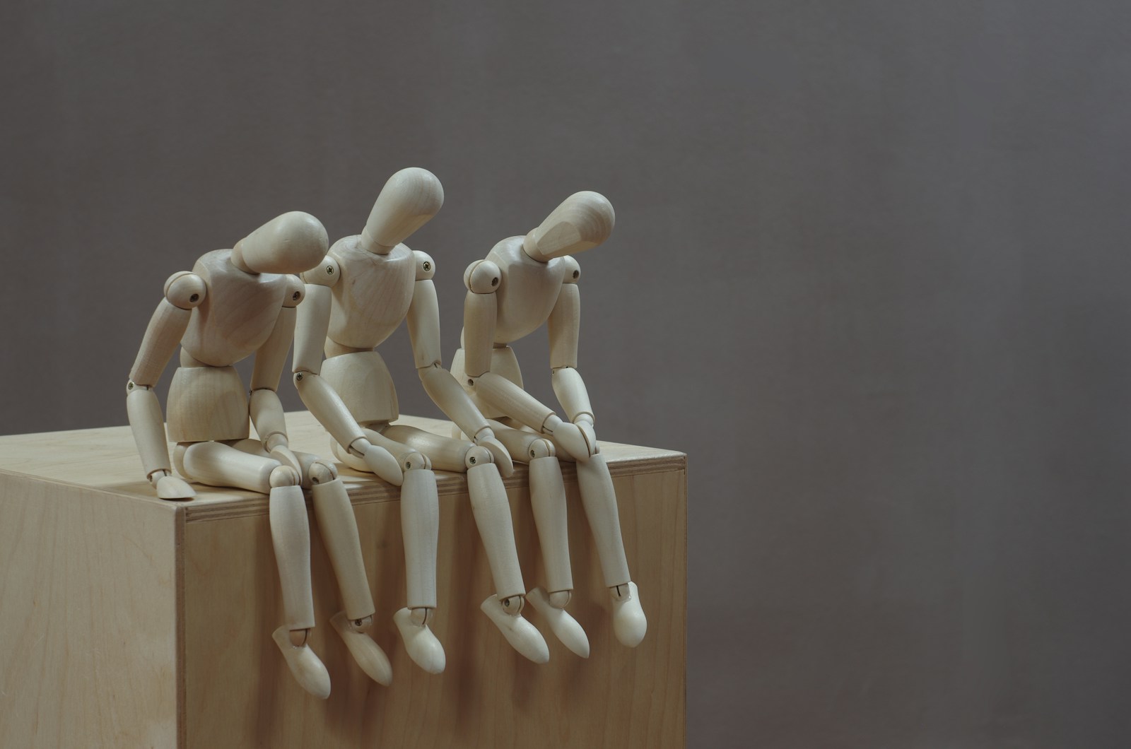a group of wooden mannequins sitting on top of a wooden block; Decision Fatigue