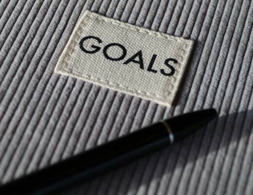 black and silver pen on gray textile financial goals planner