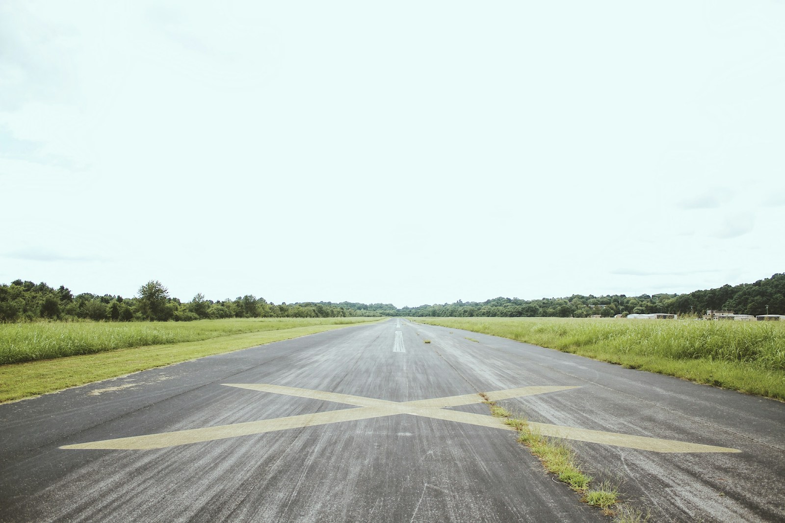 gray road surrounded by green grass during daytime; extend runway