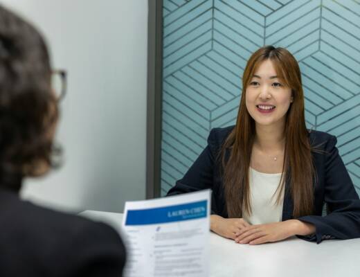 a woman sitting at a table with a piece of paper in front of her; Full-Time Hires