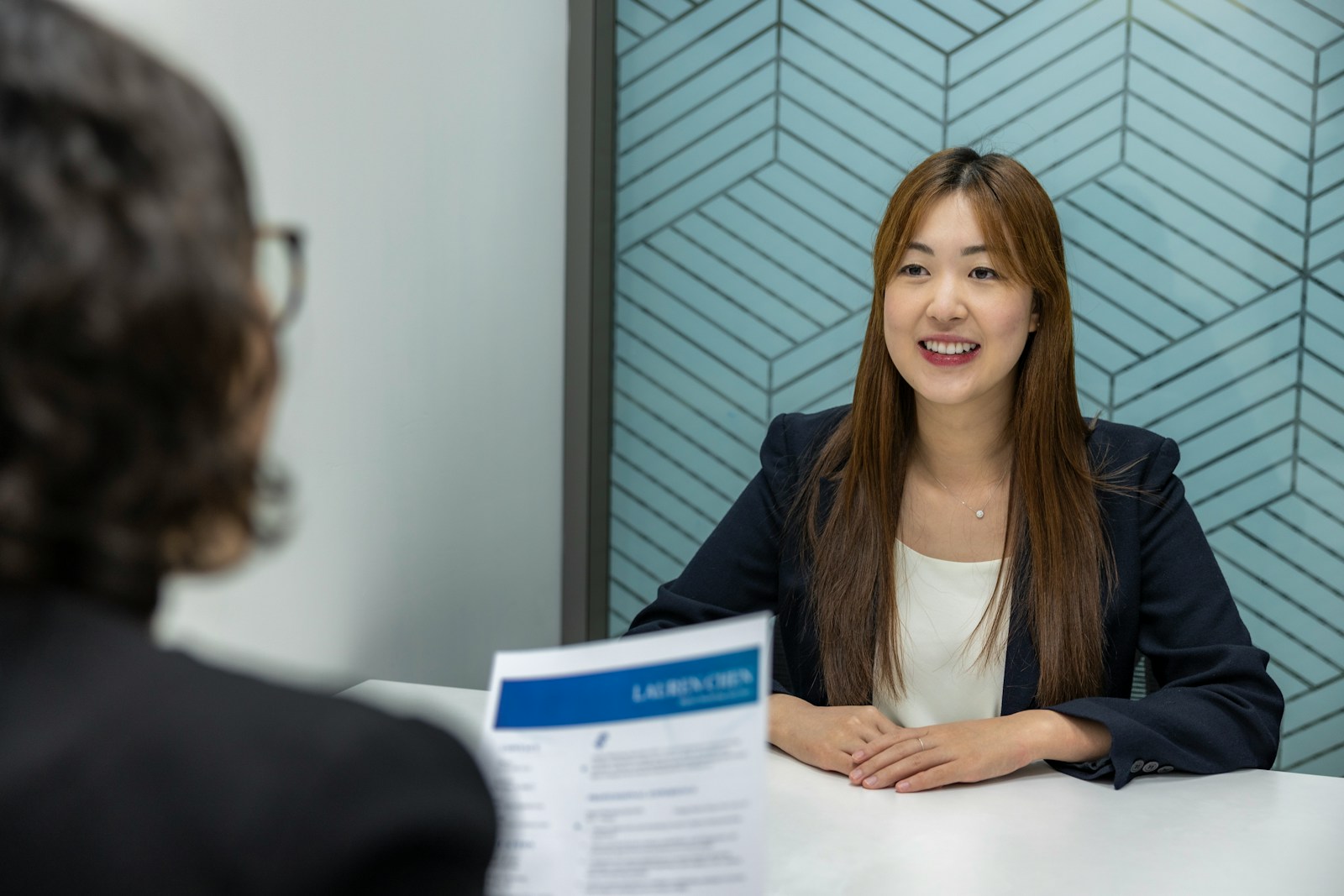 a woman sitting at a table with a piece of paper in front of her; Full-Time Hires