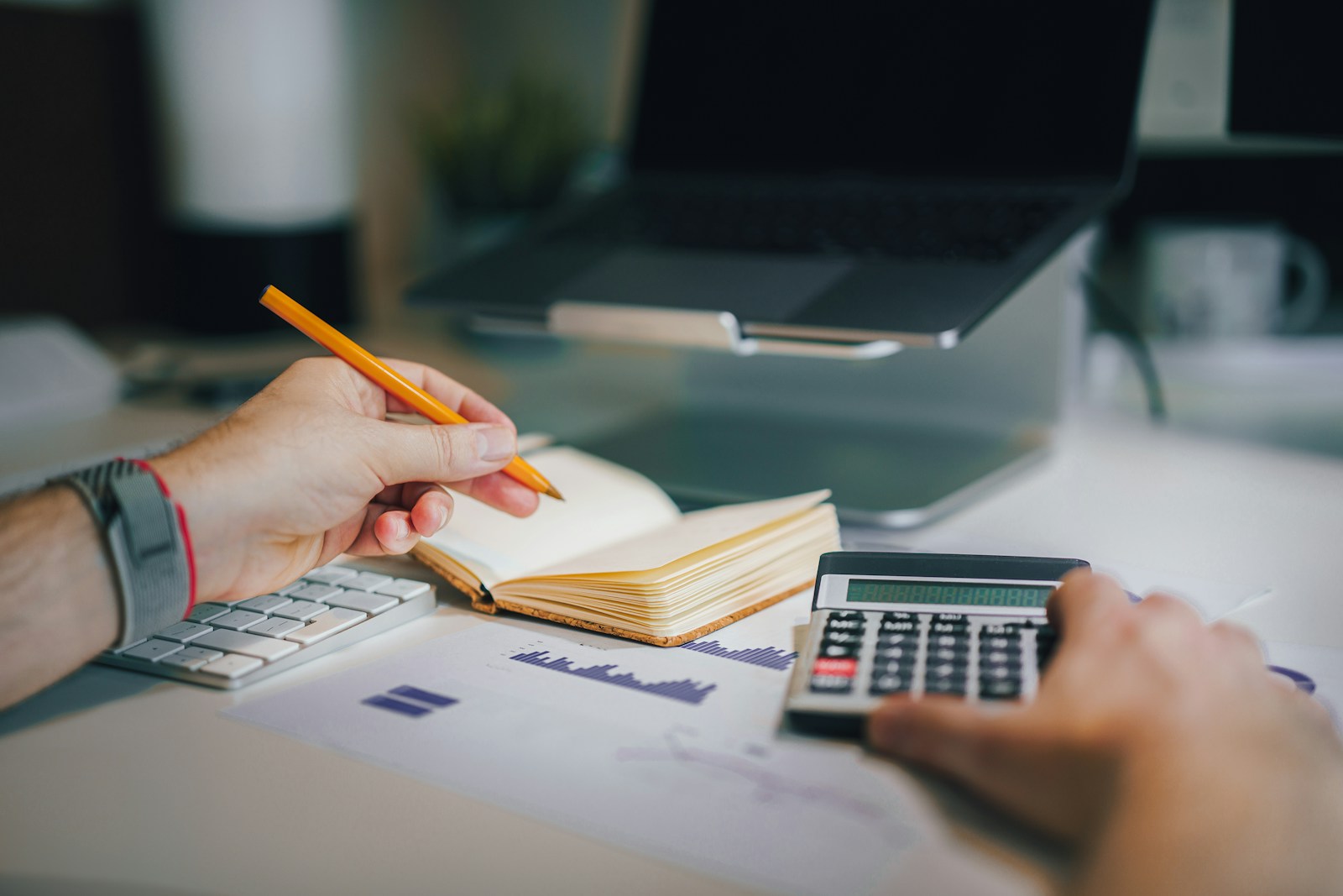 a person sitting at a desk with a calculator and a notebook; profit