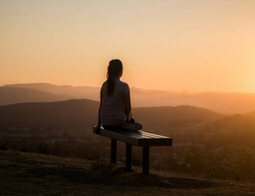 woman sitting on bench over viewing mountain; Rituals