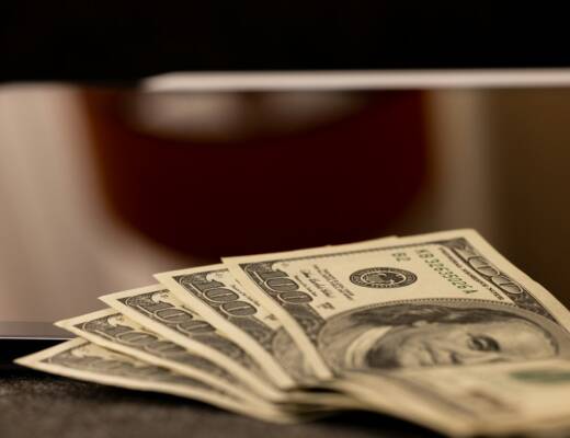 a stack of money sitting on top of a laptop computer; Underpricing Your Product