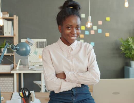 Young woman smiling with arms crossed in office; Young Founder