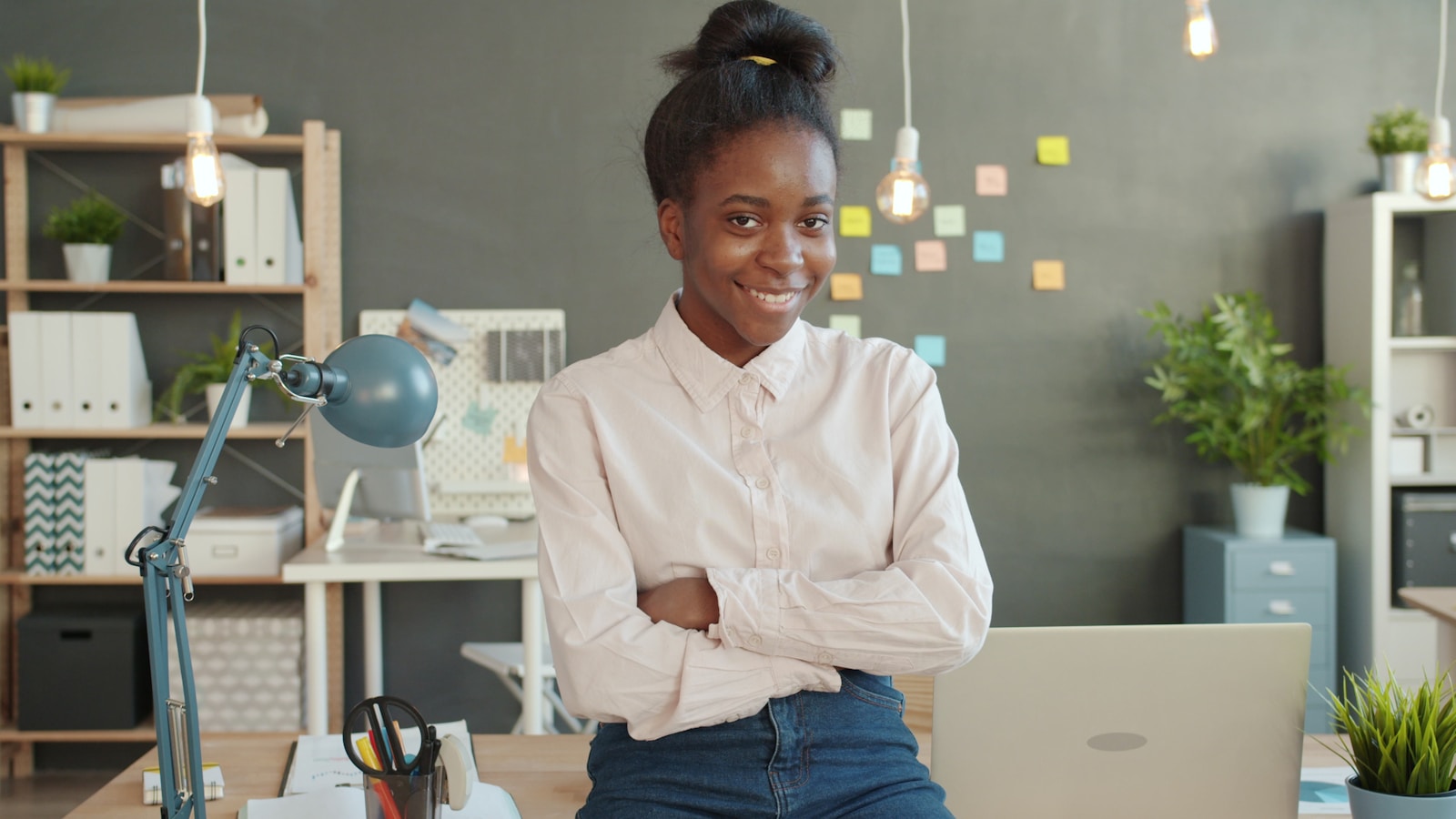Young woman smiling with arms crossed in office; Young Founder