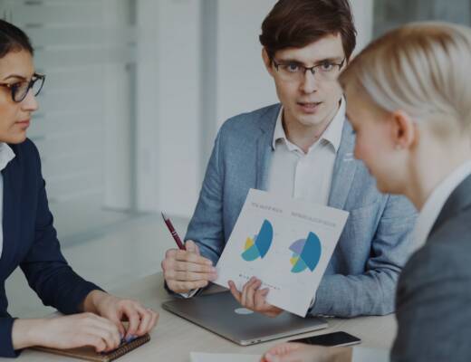 Three professionals discussing charts in a meeting; growth starts feeling expensive