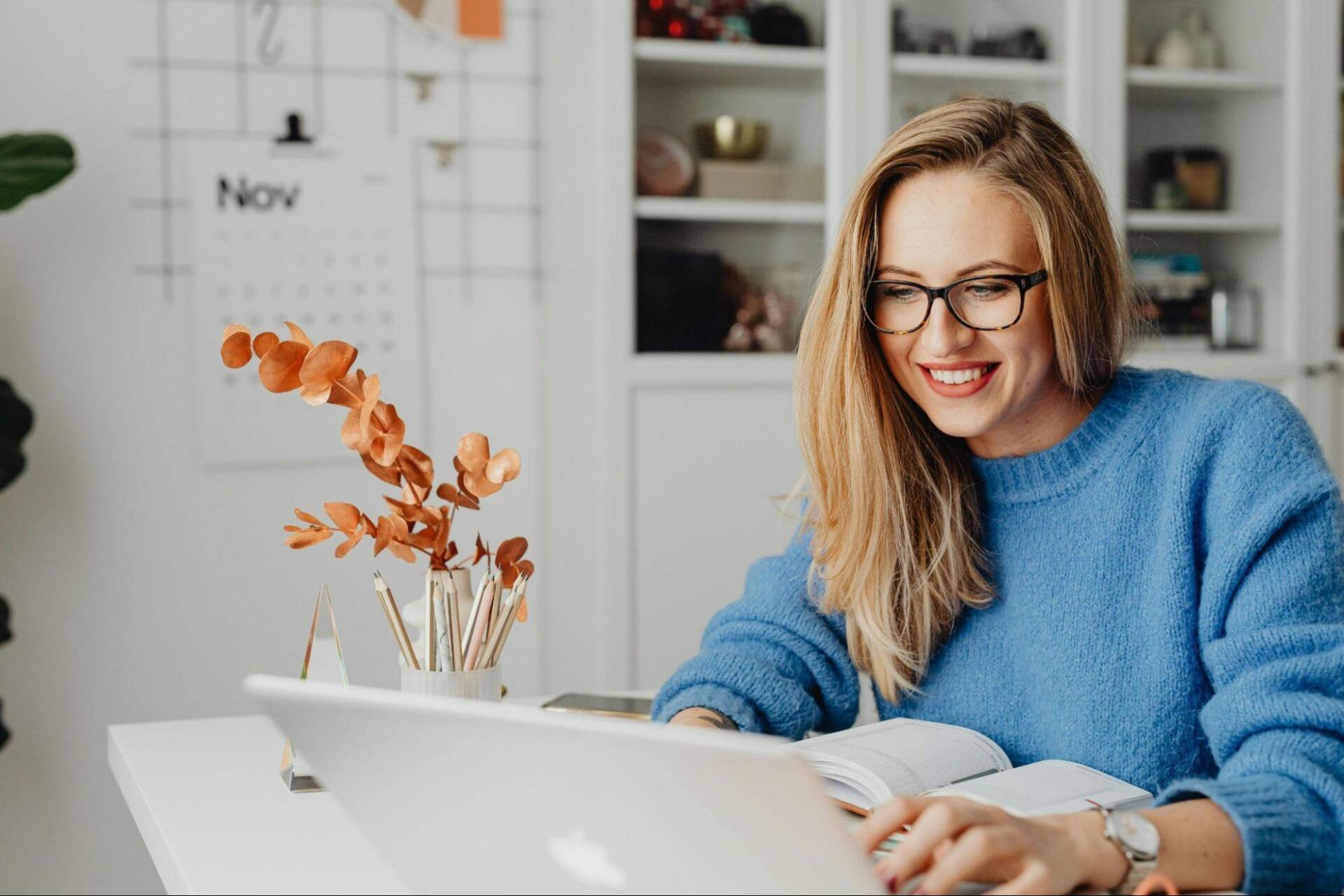 Entrepreneur wearing light blue sweater working from home and remotely managing shipping operations for her business; Free Shipping Platforms