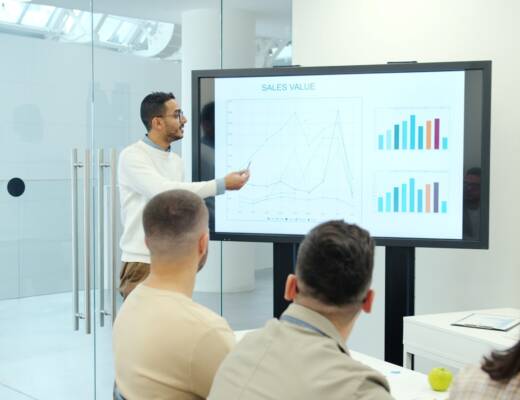 Man presenting charts on a large screen to audience; founder habits revenue stability
