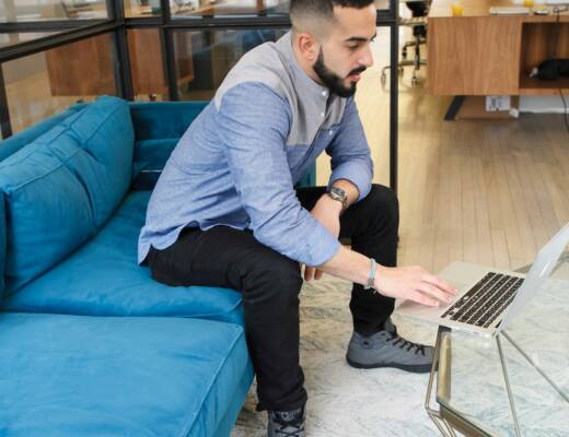 a man sitting on a couch using a laptop computer; loneliness early entrepreneurship