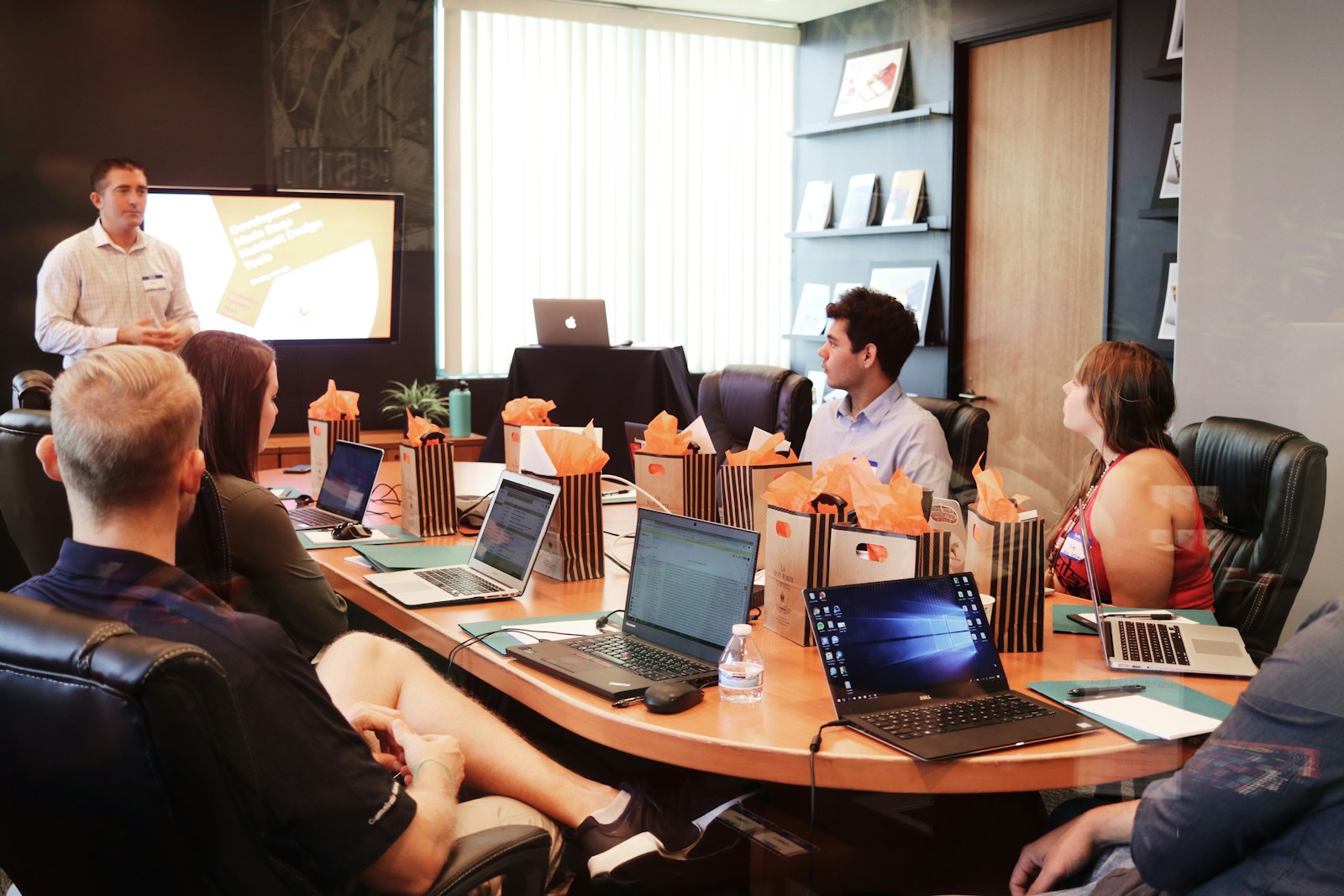 man standing in front of people sitting beside table with laptop computers; safety financial risk