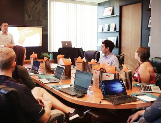 man standing in front of people sitting beside table with laptop computers; under 30 leaders