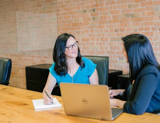 woman in teal t-shirt sitting beside woman in suit jacket; customer interviews business idea