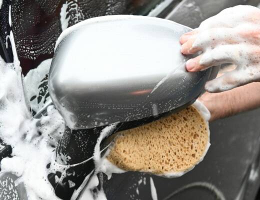 a person washing a car with a sponge; car detailing business