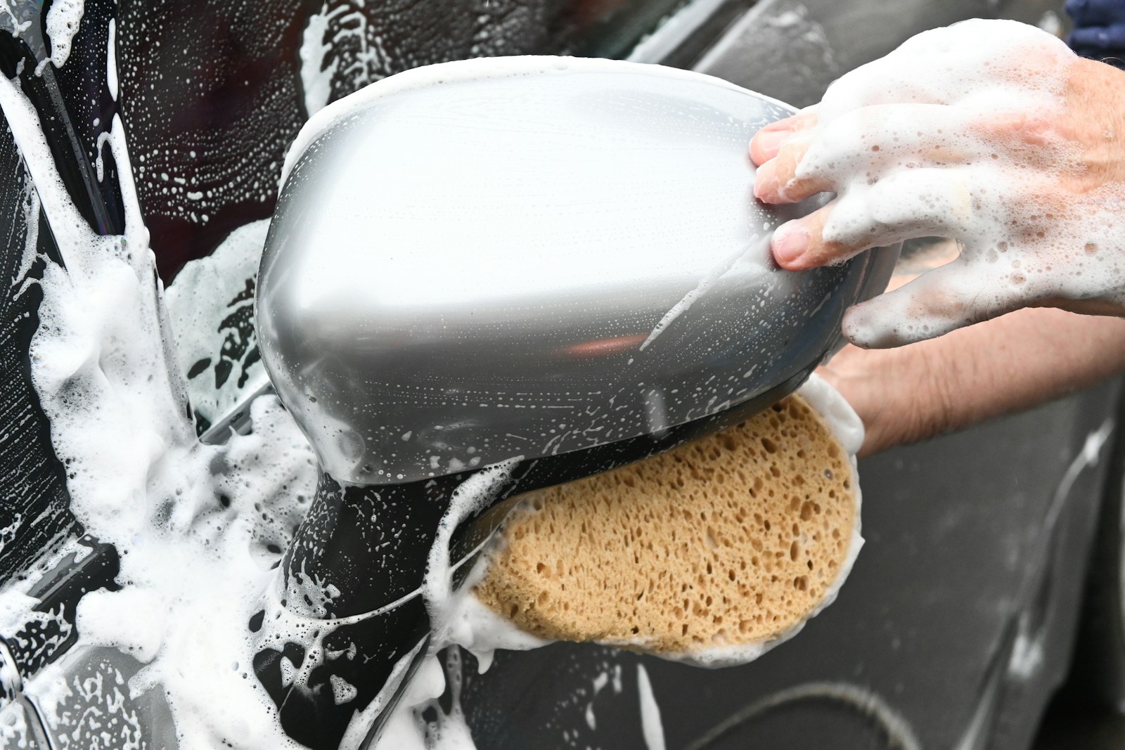a person washing a car with a sponge; car detailing business