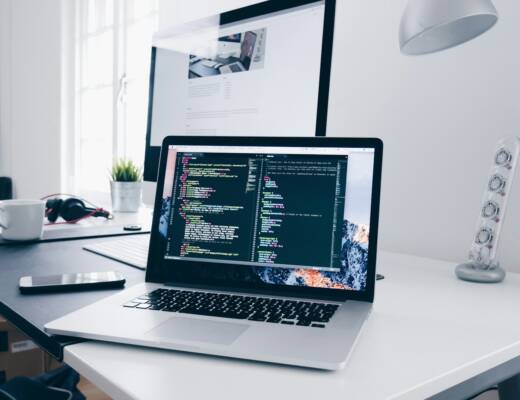 A MacBook with lines of code on its screen on a busy desk; founders protect intellectual property