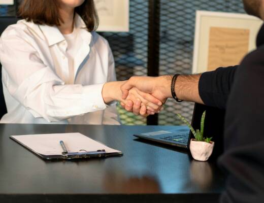 a man and a woman shaking hands in front of a laptop; employer language requirements