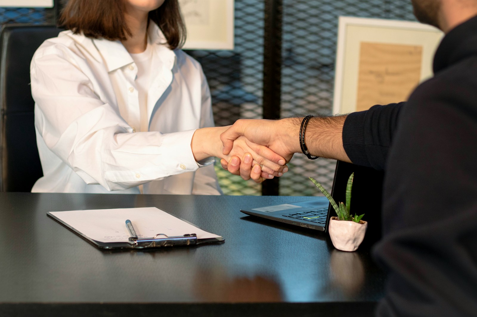 a man and a woman shaking hands in front of a laptop; employer language requirements