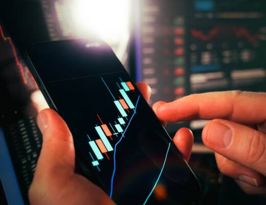 Hands holding smartphone showing stock market data; invest for growth