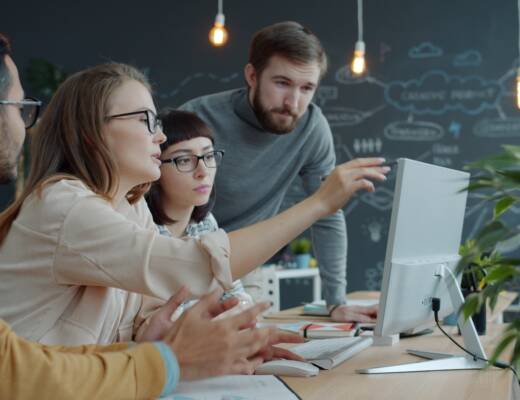 Team collaborating around a computer in an office; Team-market fit matters