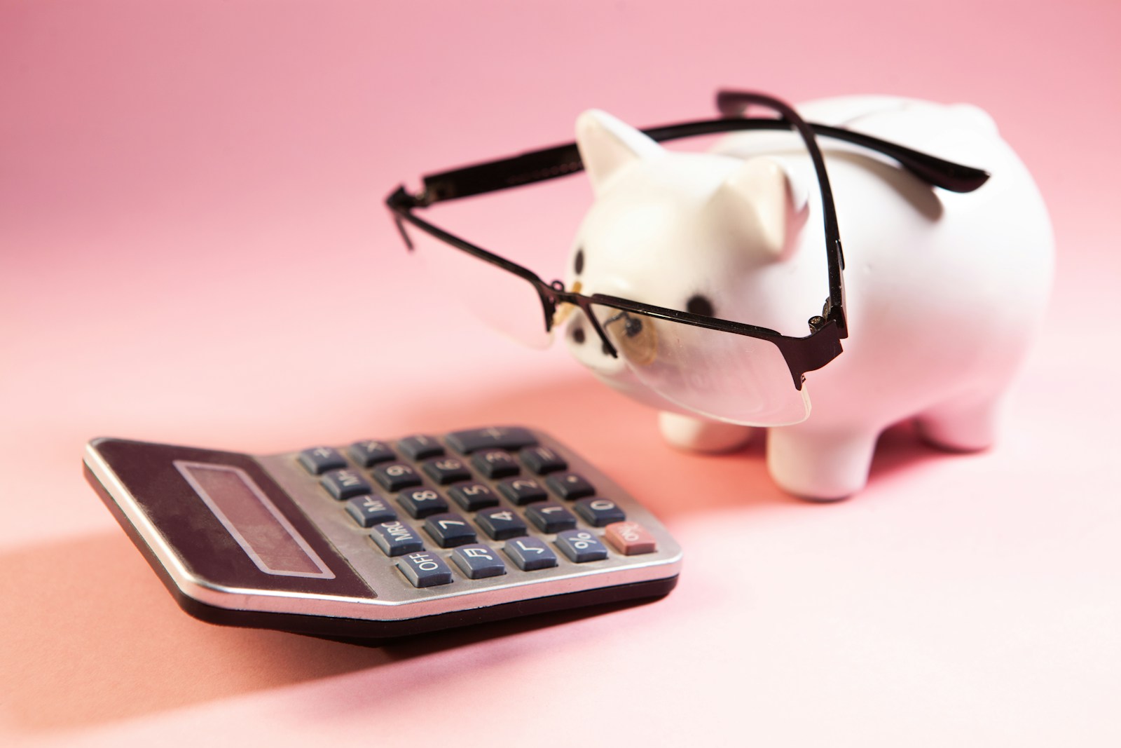 A piggy bank wearing glasses next to a calculator; financial systems save founders
