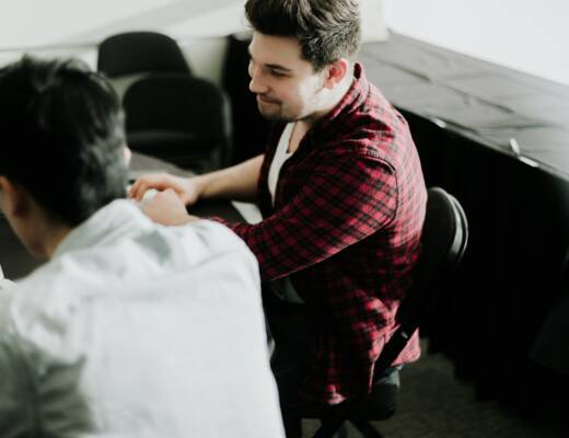 a man sitting at a desk shaking hands with another man; healthier startup signs