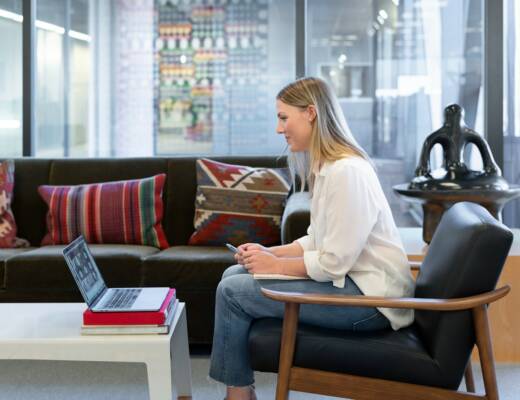 woman in white long sleeve shirt sitting on red and brown couch; navigating mergers