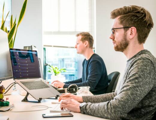 Two web developers sitting at desks working; unified system design efficiency