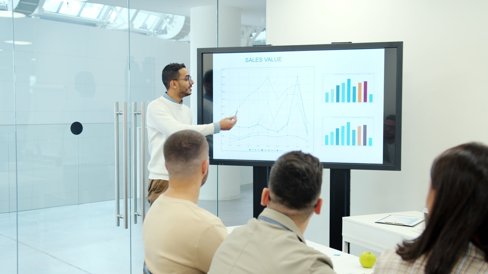 Man presenting charts on a large screen to audience; spending quietly traps founders