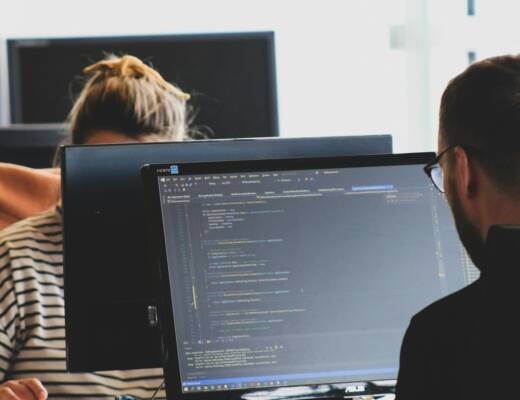 woman in black shirt sitting beside black flat screen computer monitor; AI coding growing companies