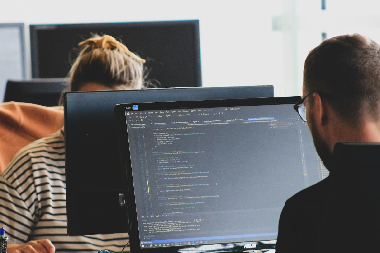 woman in black shirt sitting beside black flat screen computer monitor; AI coding growing companies
