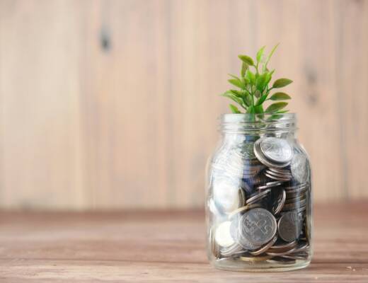 a glass jar filled with coins and a plant, representing financial growth; family compounds financial traps