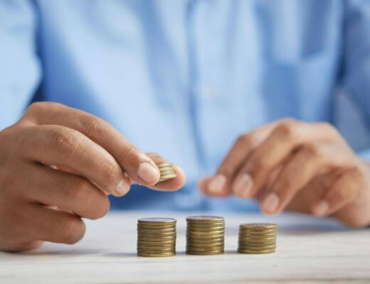 a person stacking coins on top of a table; stop worshiping status symbols