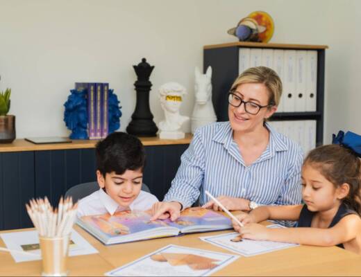 Photo of parent educating her two children using a workbook; learning depth over devices