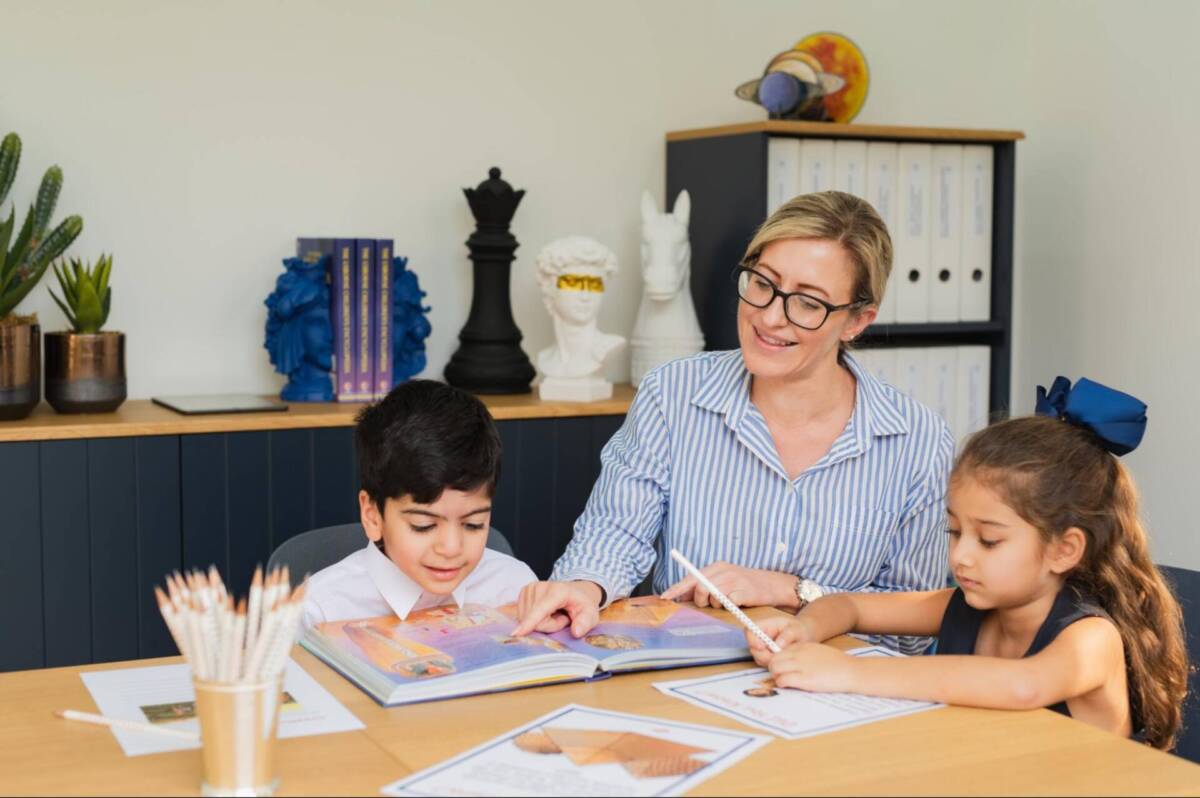 Photo of parent educating her two children using a workbook; learning depth over devices