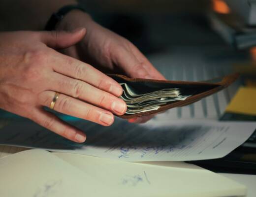 Hands holding cash in a wallet over papers; playing house separate money