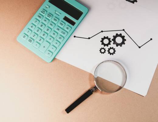 Calculator, magnifying glass, and chart with gears on paper; Tough Love Wishful Thinking