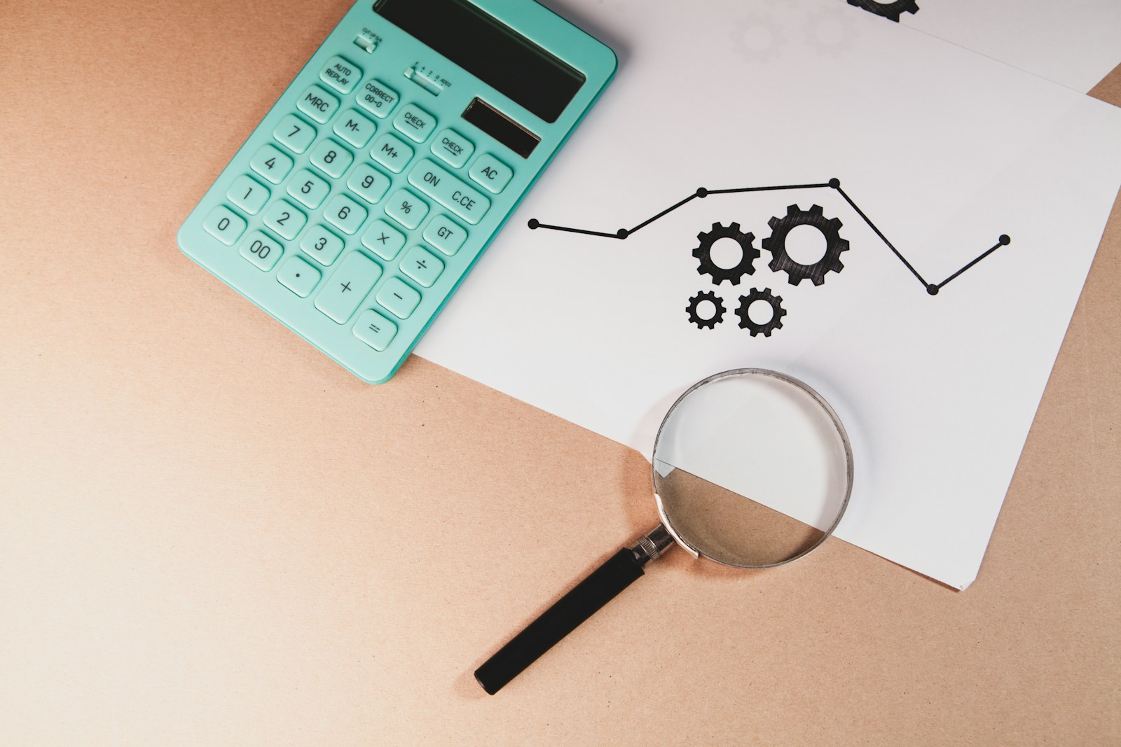 Calculator, magnifying glass, and chart with gears on paper; Tough Love Wishful Thinking