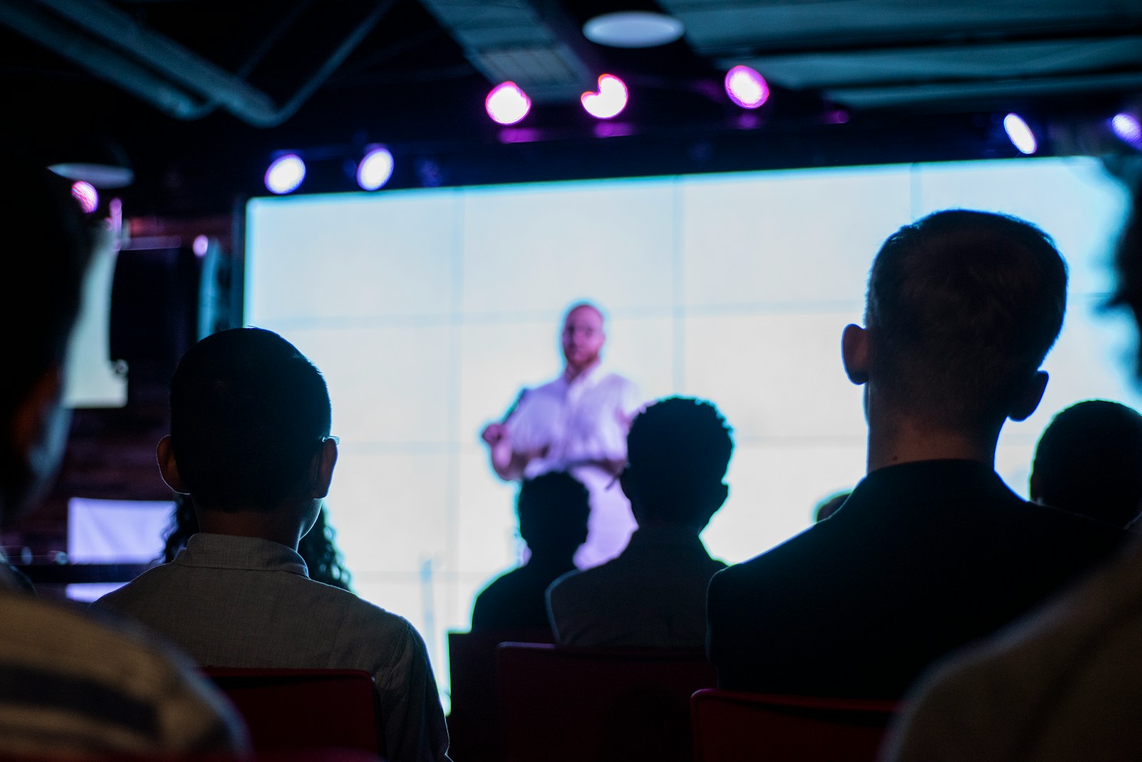 a sales speaker in black suit standing in front of people