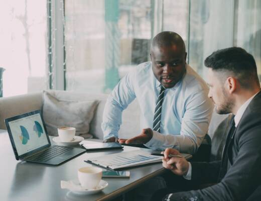 Two businessmen discussing growth charts on a laptop; scalable growth not noise