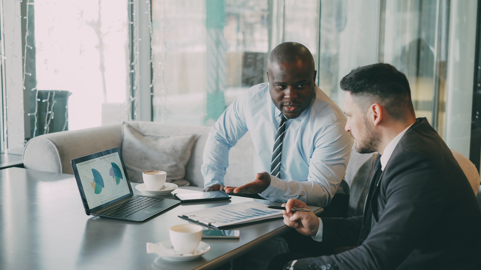 Two businessmen discussing growth charts on a laptop; scalable growth not noise