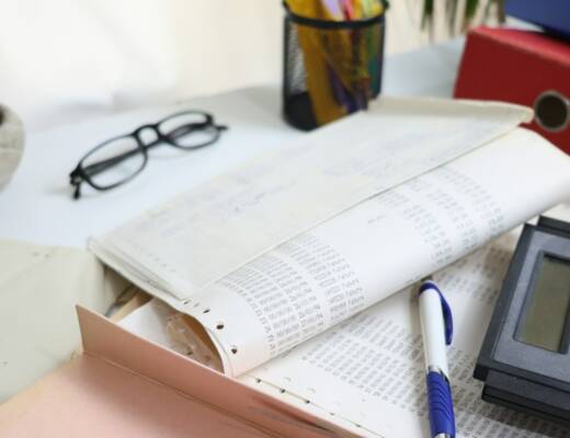 Desk with papers, glasses, calculator, and office supplies; underpaying yourself killing business