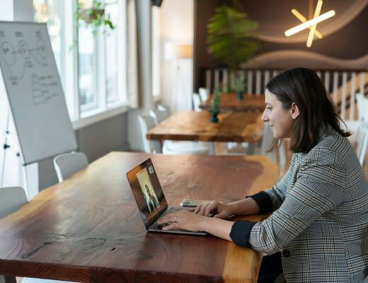 woman in gray blazer using laptop to have a video call with a customer; conversational AI sales teams