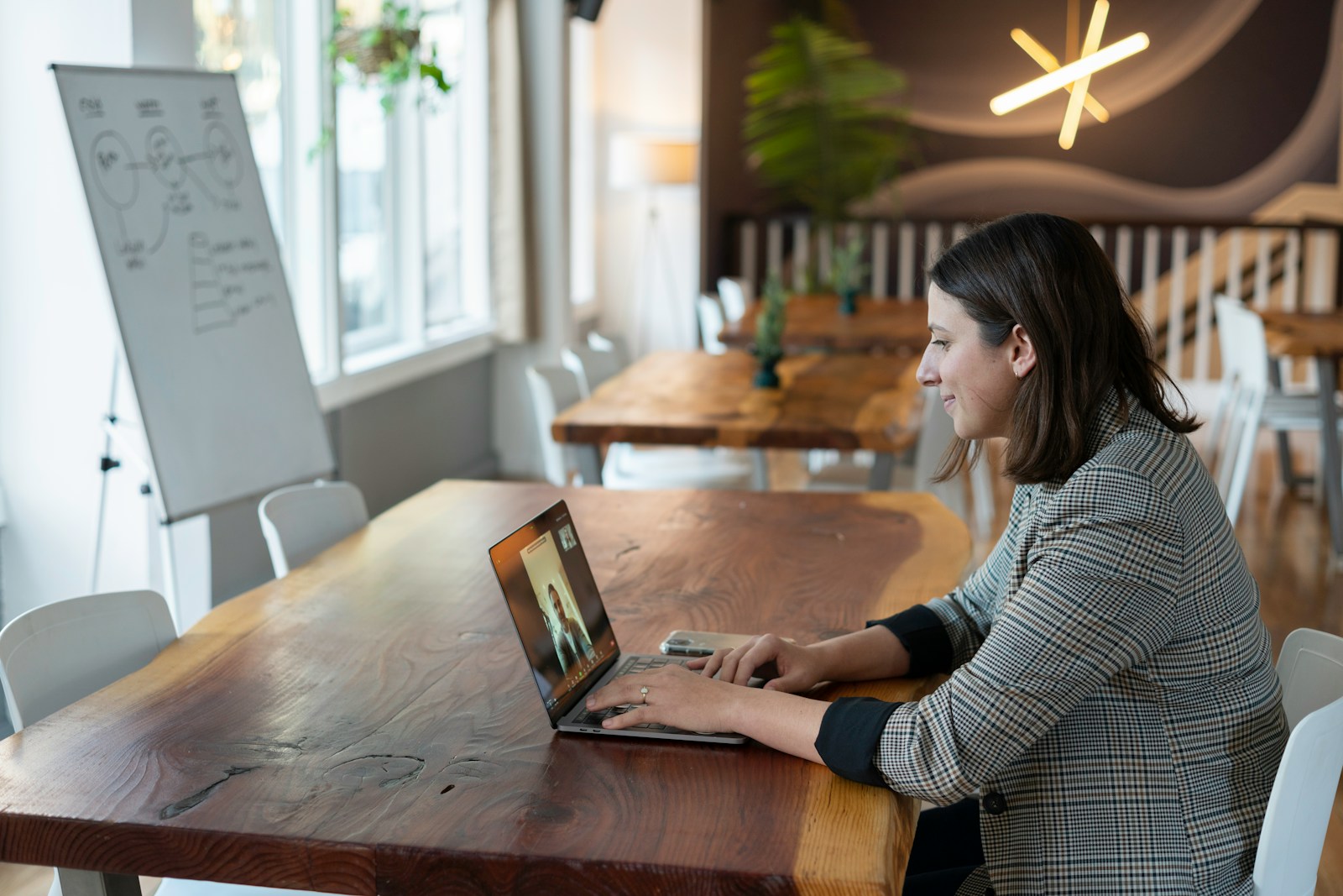 woman in gray blazer using laptop to have a video call with a customer; conversational AI sales teams
